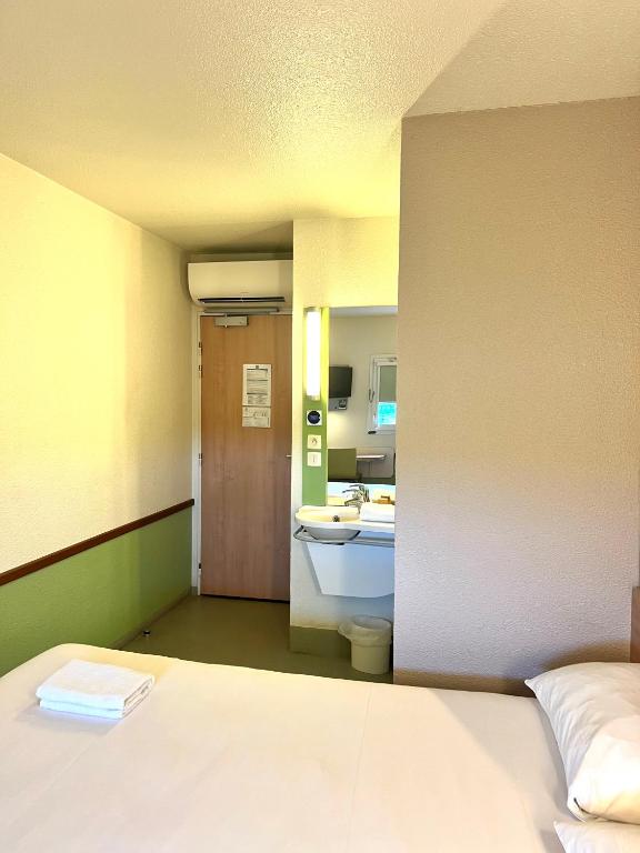 a room with a bed and a bathroom with a sink at Hotel Ibis Budget Cosne Sur Loire in Cosne-Cours-sur-Loire