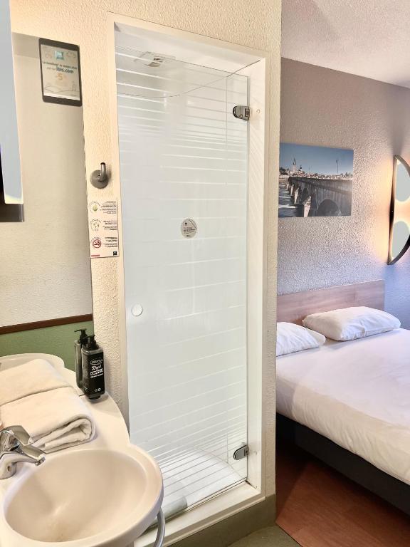 a bathroom with a sink and a shower with a bed at Hotel Ibis Budget Cosne Sur Loire in Cosne-Cours-sur-Loire