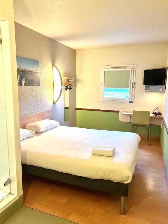 a bedroom with a bed and a desk and a window at Hotel Ibis Budget Cosne Sur Loire in Cosne-Cours-sur-Loire