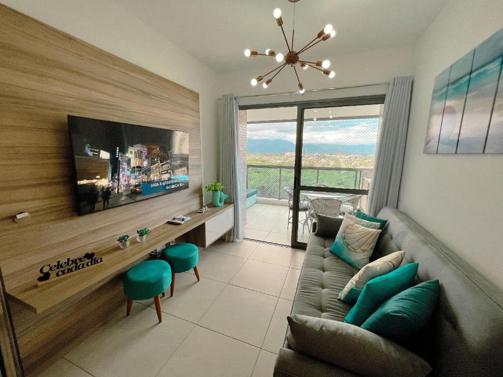 un salon avec un canapé et une télévision dans l'établissement Home 49 I Apto pé na areia e piscina aquecida em Bertioga, à Bertioga