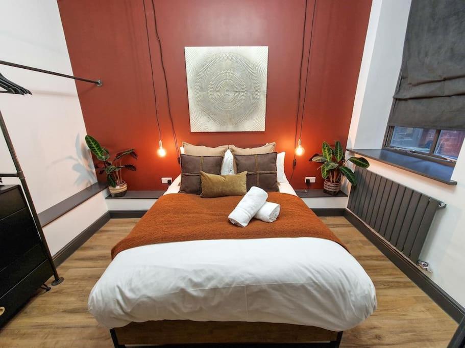 a bedroom with a large bed with orange walls at Stunning Northern Quarter Flat in Manchester