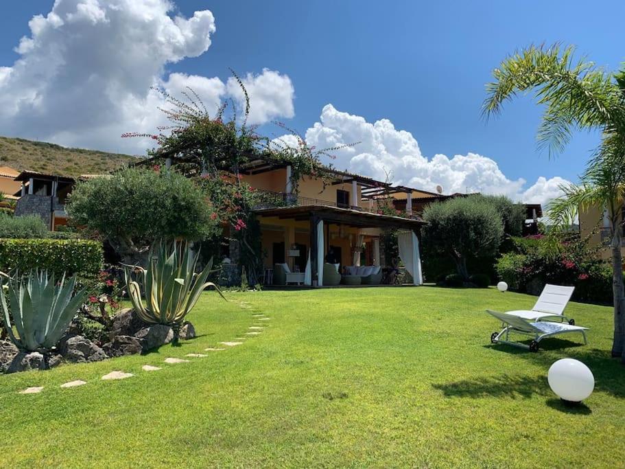 a house with a lawn with a chair in the yard at Luxury villa al mare in Calabria Diamante in Cirella