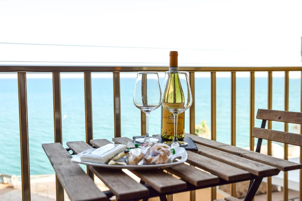 a wooden table with a bottle and glasses on a balcony at STELLA MARINA VACATION in Pozzallo