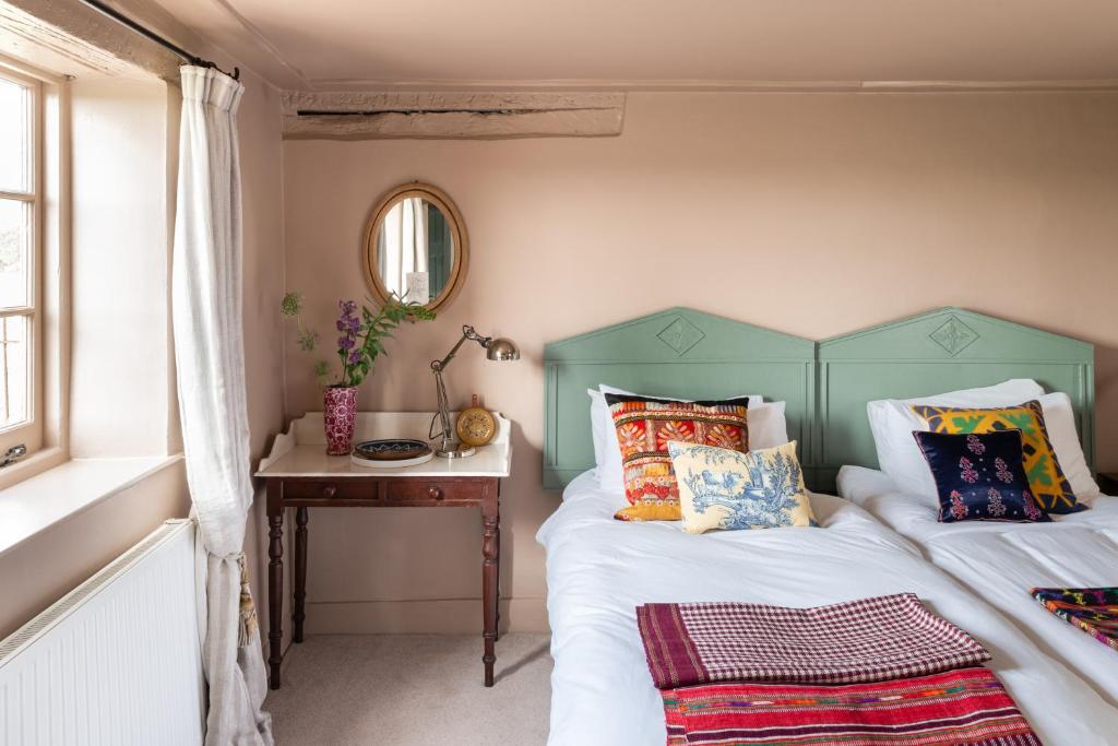 a bedroom with two beds and a table with a mirror at Apple Cottage - Vivre Retreats in Wimborne Minster