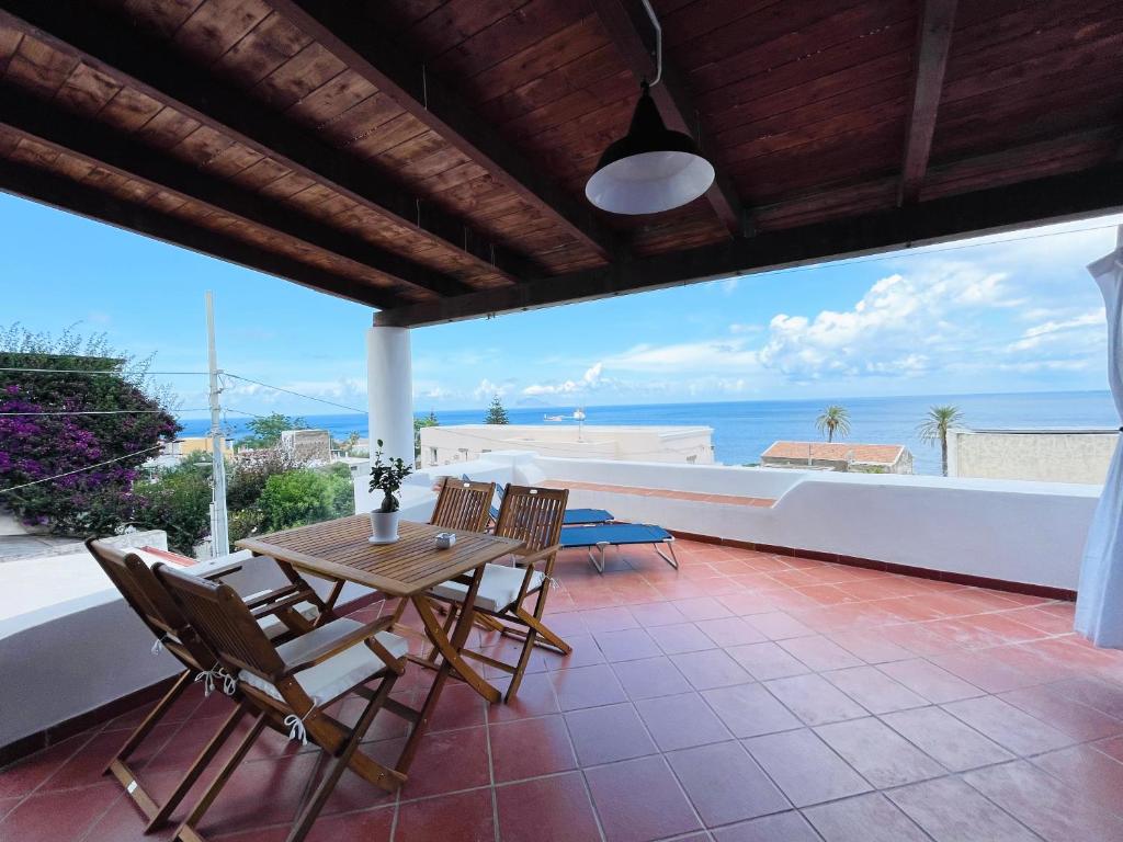 un patio con mesa, sillas y el océano en Villa Margherita - Appartamenti a due passi dal corso di Santa Marina Salina a 100 mt dalla spiaggia, en Santa Marina Salina