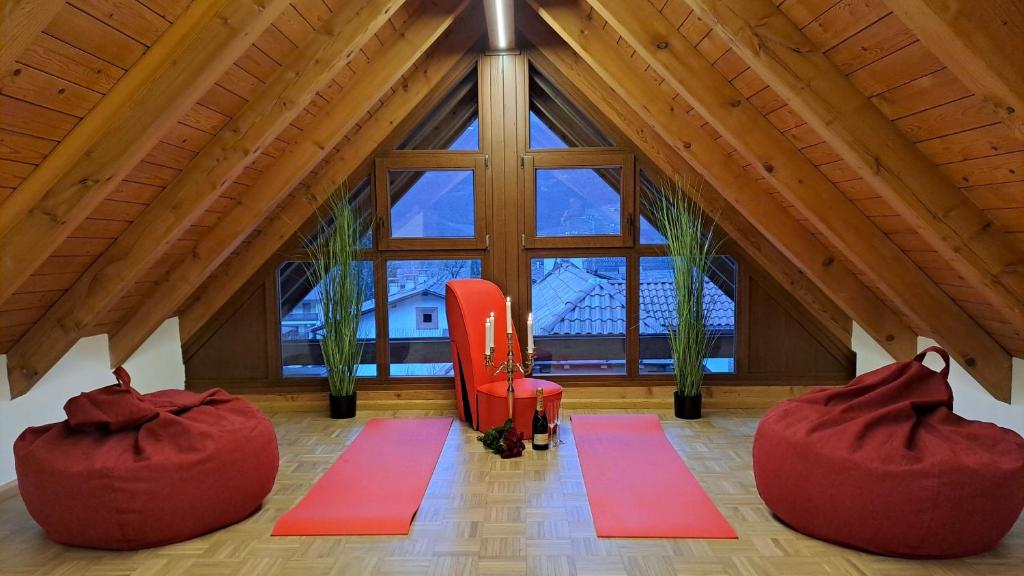 an attic room with red chairs and a large window at Penthouse&Wellness L'Abete in Gargazzone