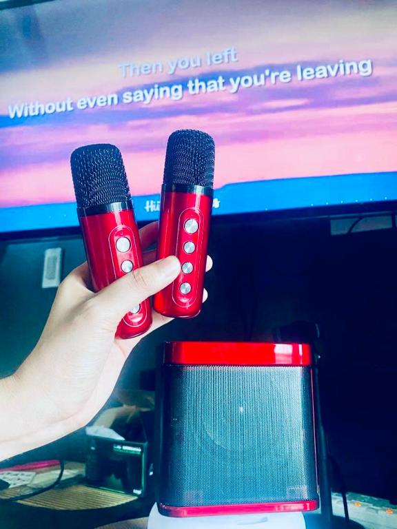 a person holding two microphones in front of a computer screen at Azure staycation by C&N in Manila
