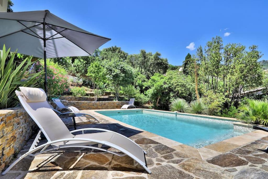 une piscine avec deux chaises et un parasol dans l'établissement Calme, Piscine - Appartement Milady's Garden, à Bormes-les-Mimosas