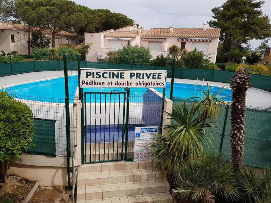 een hek met een bord voor een zwembad bij Rez de jardin Pinède Proximité Quartier Naturiste in Cap d'Agde