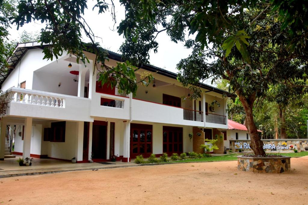 un edificio con un árbol delante de él en Ranathisara Grand Hotel en Kurunegala