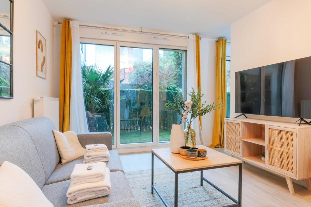 un salon avec un canapé et une télévision dans l'établissement A Cozy Nest with Garden - Montreuil - 1BR 4P, à Montreuil