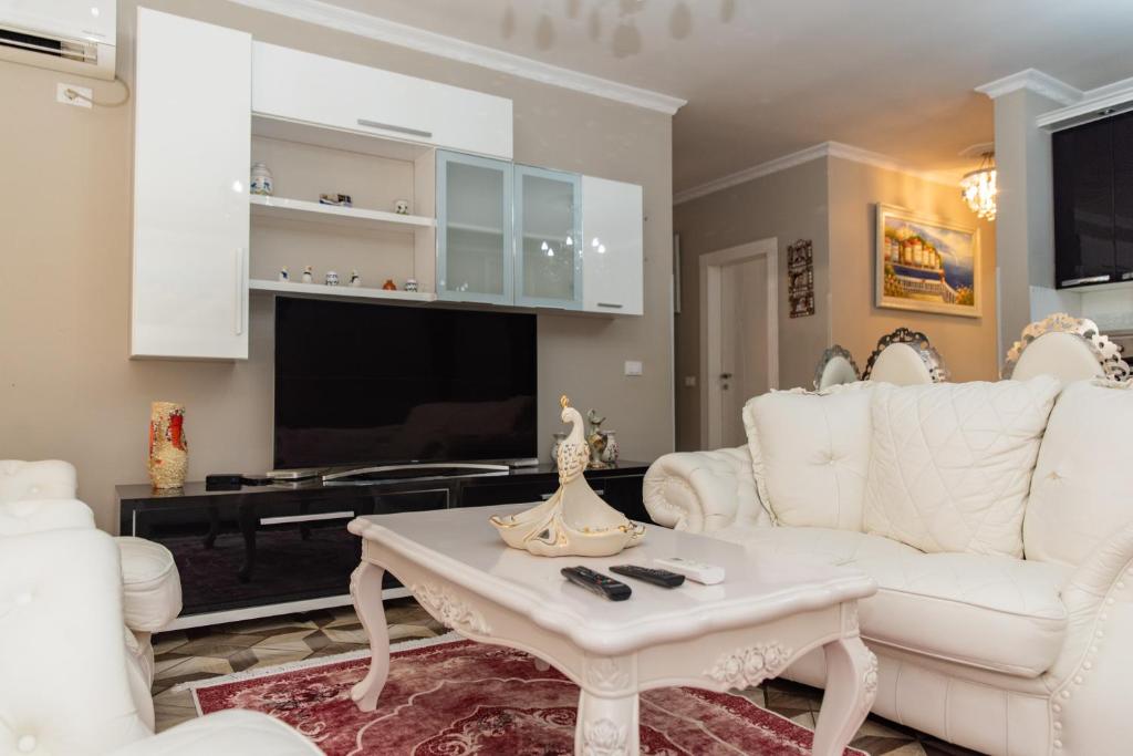 a living room with white furniture and a flat screen tv at Beach Heaven Apartments in Durrës