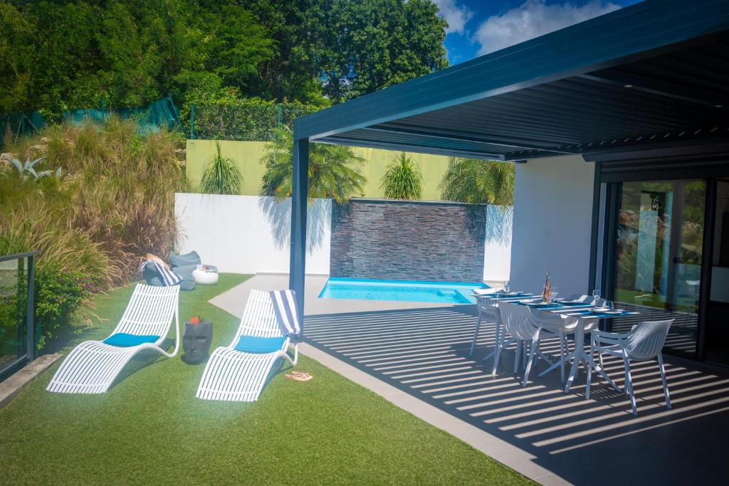 a patio with a table and chairs and a pool at Tropic &amp; Chic in Sainte-Anne