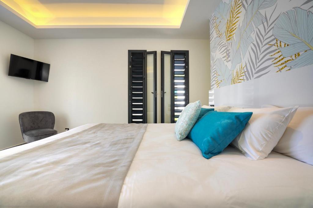 a bedroom with a large white bed with blue pillows at Tropic &amp; Chic in Sainte-Anne