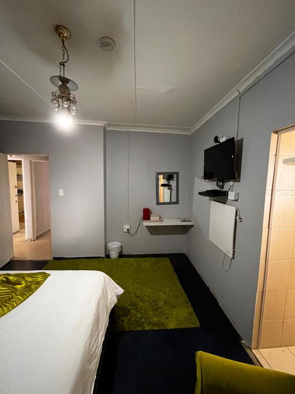 1 dormitorio con cama blanca y alfombra verde en E.G Guest House, en Kokstad