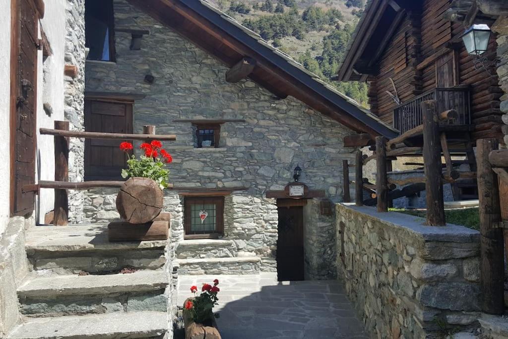 a stone building with a vase with red flowers in it at Chalet in pietra in Antey-Saint-André