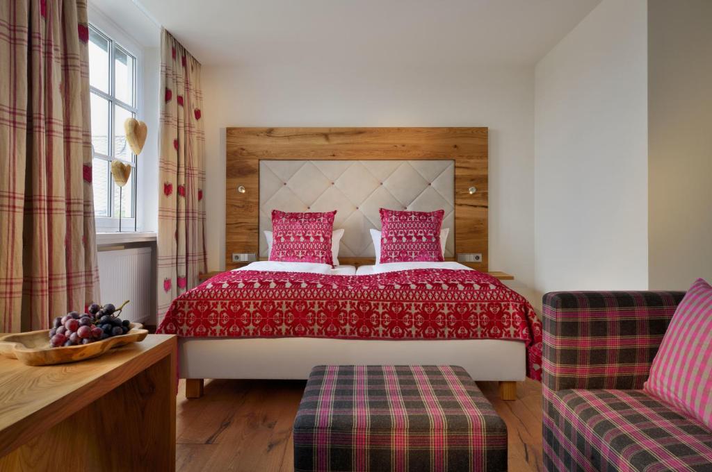 ein Schlafzimmer mit einem großen Bett mit einer roten Tagesdecke in der Unterkunft Romantik Hotel Knippschild in Rüthen