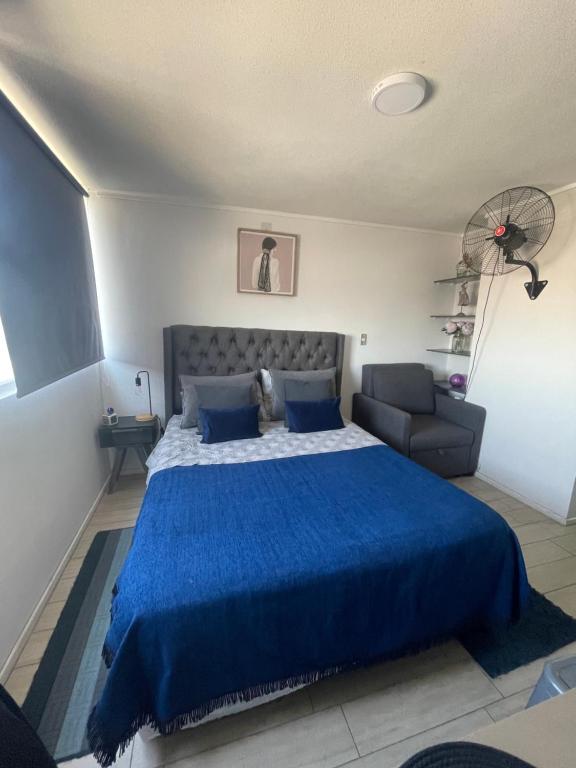 um quarto com uma cama azul e um sofá em Departamento en Santiago centro cerca de movistar arena, Caupolican em Santiago