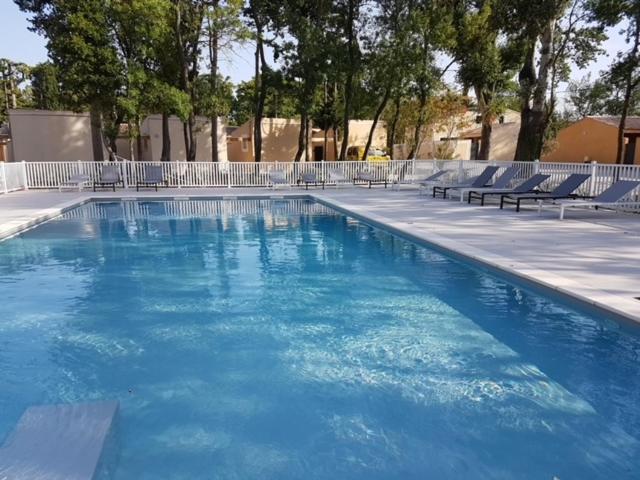 une grande piscine avec de l'eau bleue et des chaises dans l'établissement Bastidon Résidence les Alpilles, à Saint-Rémy-de-Provence