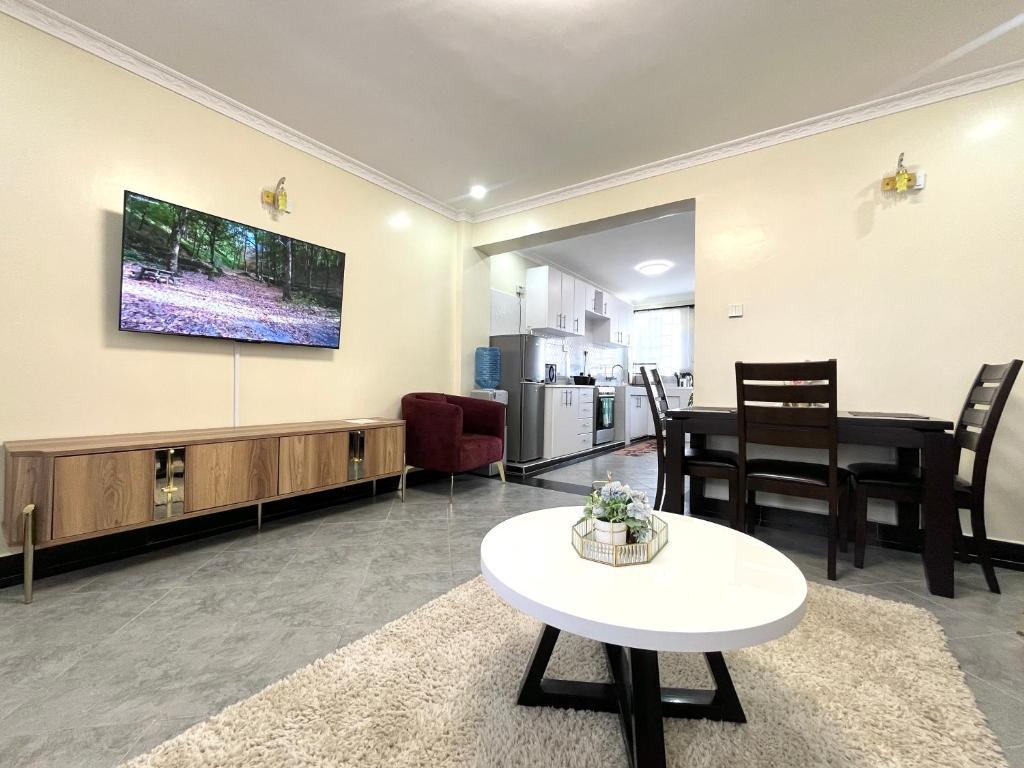 sala de estar con mesa y TV en la pared en Naka Executive Suites With Balcony, Amazing Lake Nakuru View, GYM en Nakuru