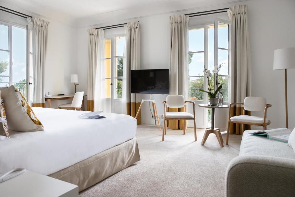 a bedroom with a large bed and a living room at Hotel Royal-Riviera in Saint-Jean-Cap-Ferrat