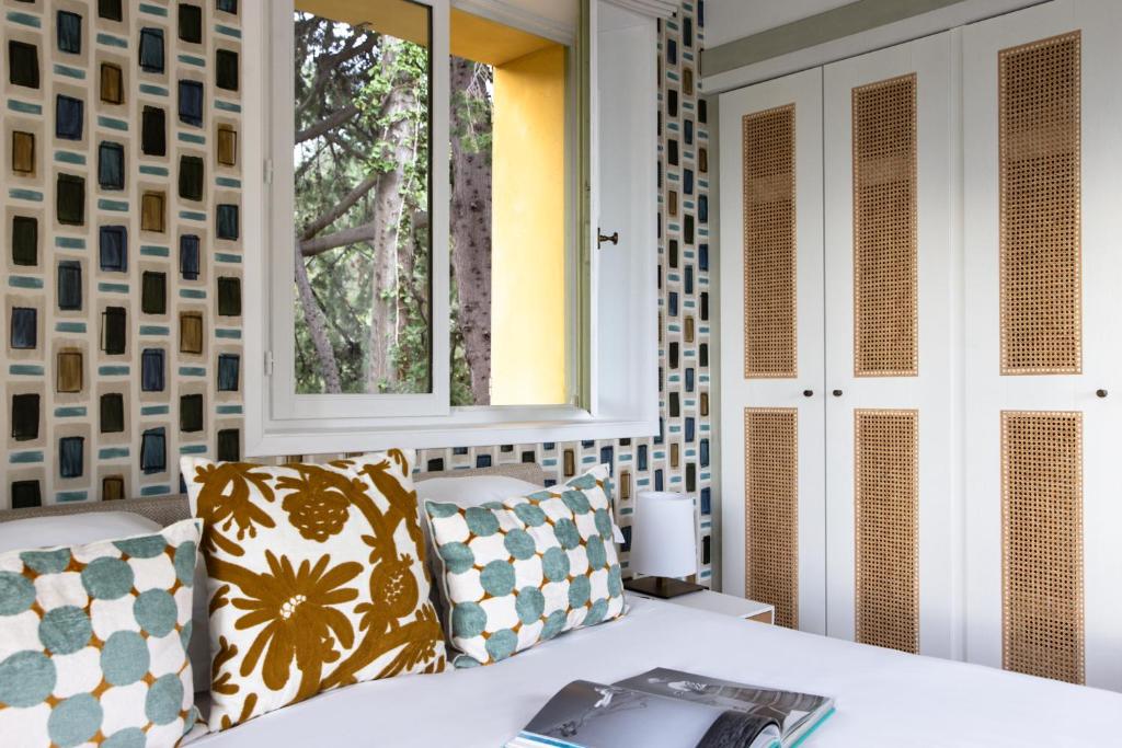 a bed with two pillows and a window in a room at Hotel Royal-Riviera in Saint-Jean-Cap-Ferrat