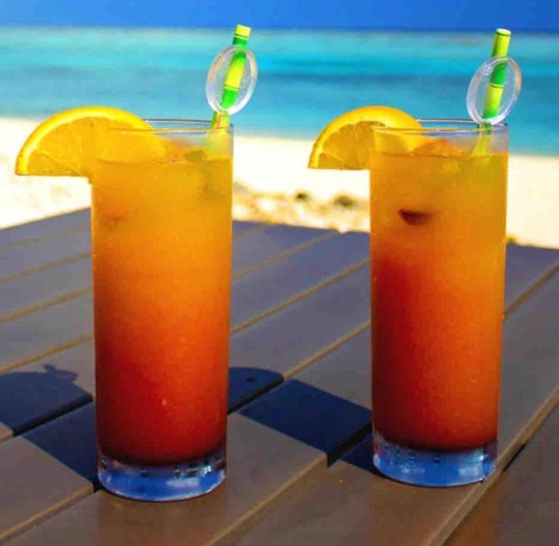 dos vasos de zumo de naranja en una mesa cerca de la playa en Annoncé supprimée, en Gustavia