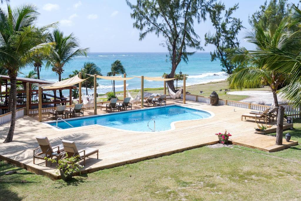 una piscina con terraza de madera y la playa en Surfers Bay Resort, en Christ Church