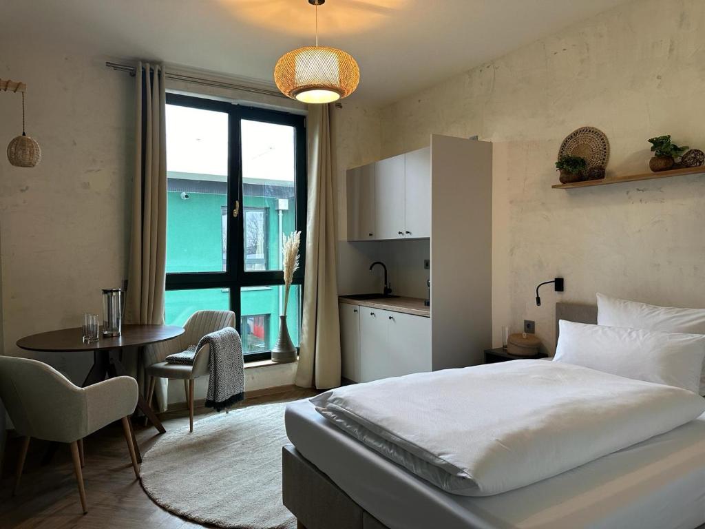 a bedroom with a bed and a table and a kitchen at PHIL & MAX Hotel und Apartments in Hannover