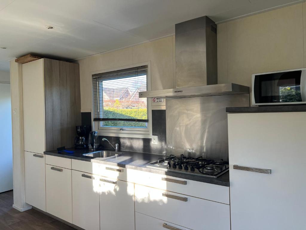 una cucina con armadi bianchi e piano cottura di Chalet 102 a Voorthuizen