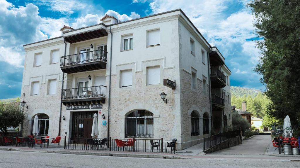 ein weißes Gebäude mit Tischen und Stühlen davor in der Unterkunft Hostal Rural Amador in Puente de Vadillos