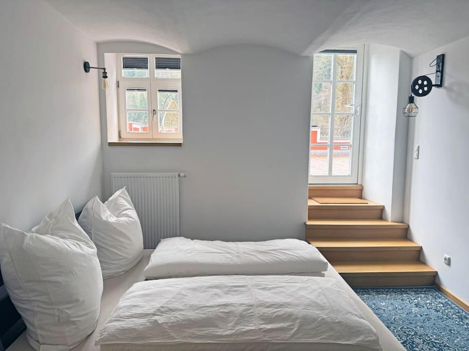 ein Schlafzimmer mit einem Bett mit weißen Kissen und einer Treppe in der Unterkunft Terrassenwohnung mit Donaublick in Obernzell