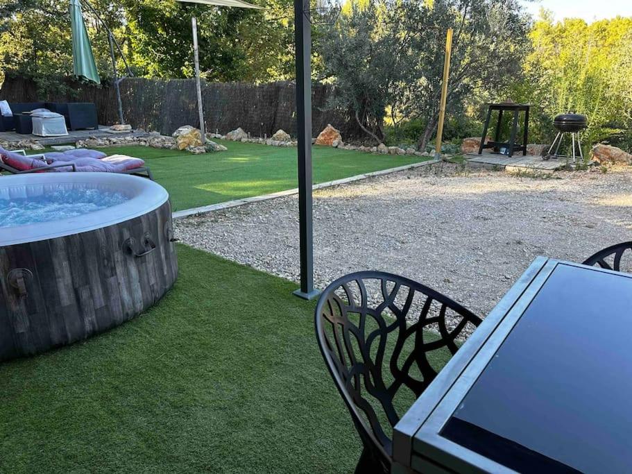 une terrasse avec un bain à remous, une table et des chaises dans l'établissement Mini house jaccuzi campagne proche mer&lac, à Flayosc