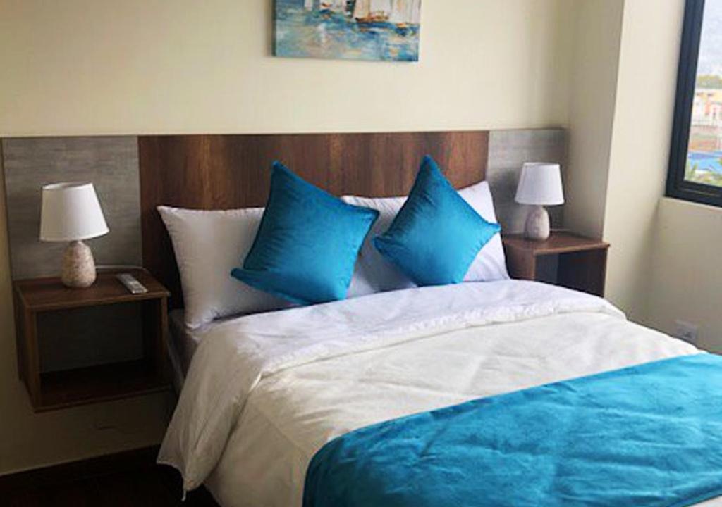 a bedroom with a large bed with blue pillows at Hotel Suites La Fontana in Ambato