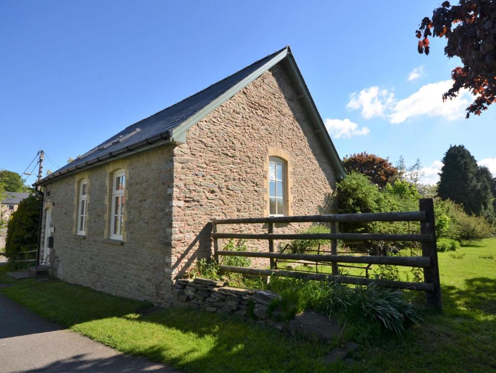 um edifício de tijolos com uma cerca de madeira em frente em 2 Bed in Hay-on-Wye 74316 em Painscastle