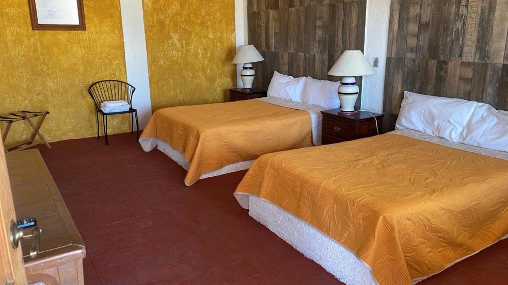 um quarto de hotel com duas camas e uma cadeira em Hotel Terraza Los cabos em Cabo San Lucas