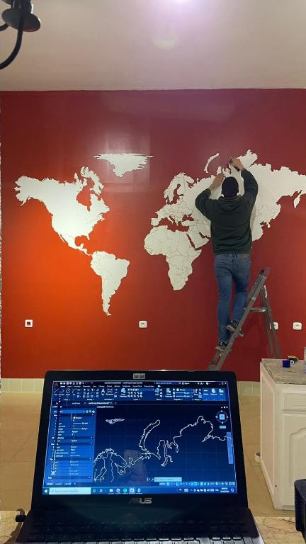 a man on a ladder painting a map on a wall at Nomads Hostel Tunisia in Tunis