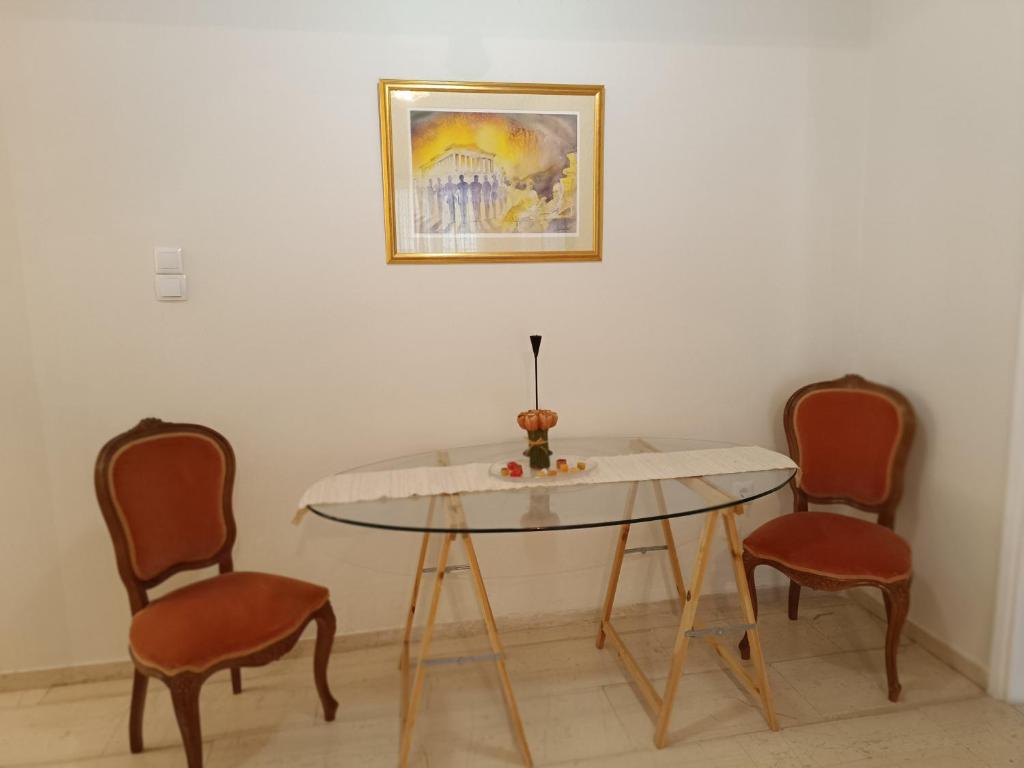 uma mesa de jantar com duas cadeiras e um quadro em Your Athens home em Atenas