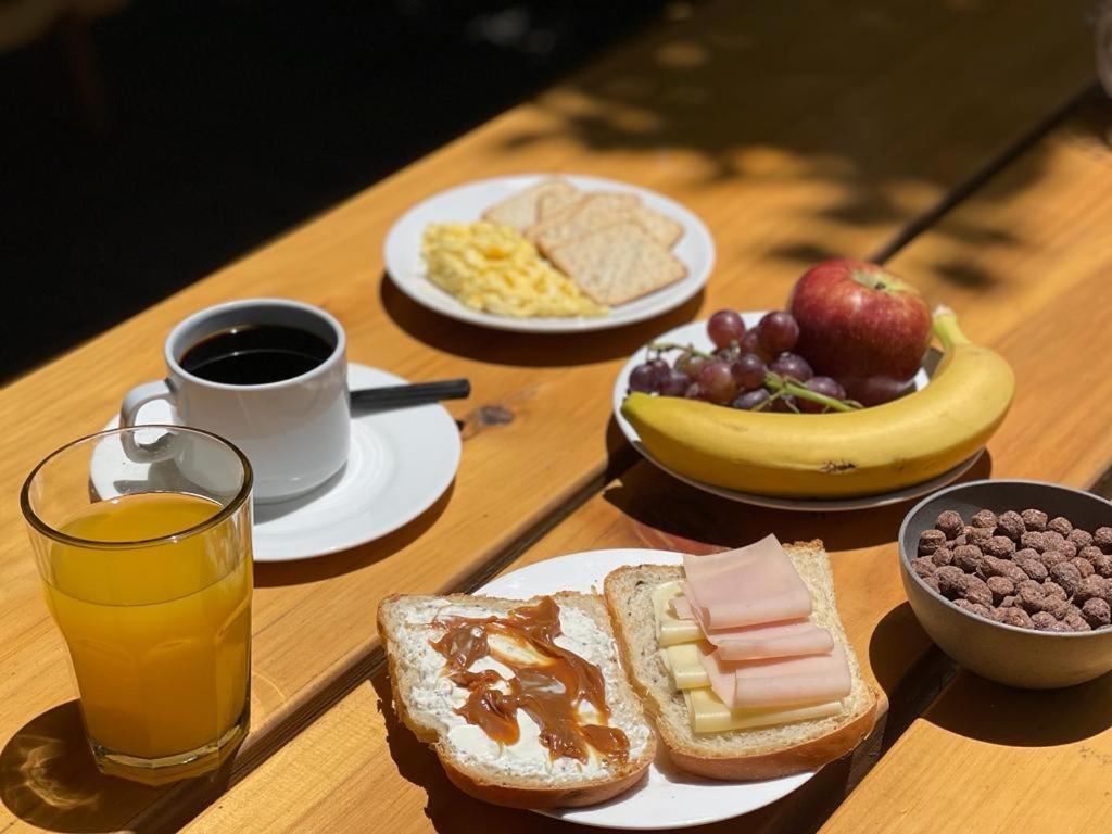 a table with plates of breakfast foods and a cup of coffee at Mora Hostel in Mendoza