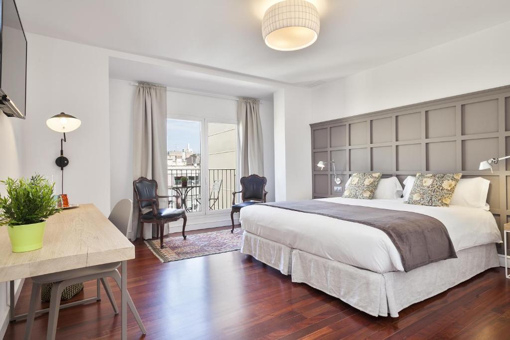 um quarto com uma grande cama branca e uma mesa em Milton House Gran Via em Barcelona