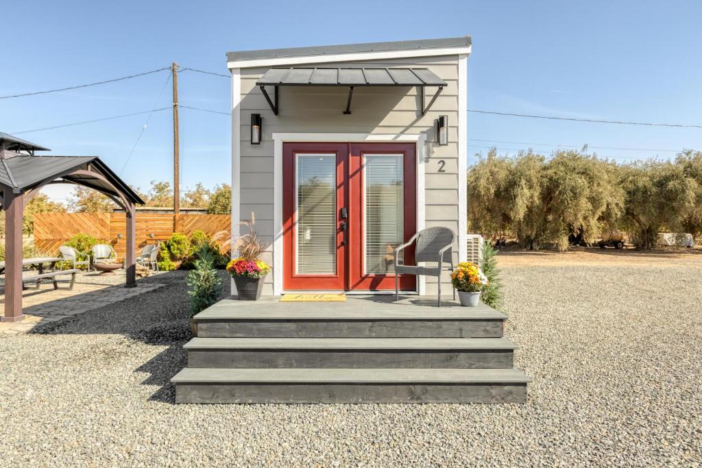 a tiny house with a red door and stairs at Red Door Tiny Home Lewis Ranch in Lindsay