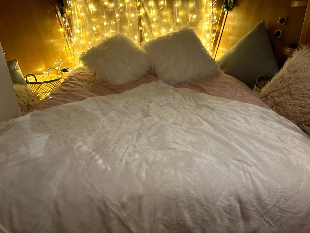 a bed with white sheets and pillows with lights at LOFT SUR L'EAU AVEC BALNEO in Cergy