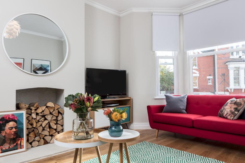 a living room with a red couch and a fire place at Madison Hill - Byrne Garden 1 - Two bedroom home in London