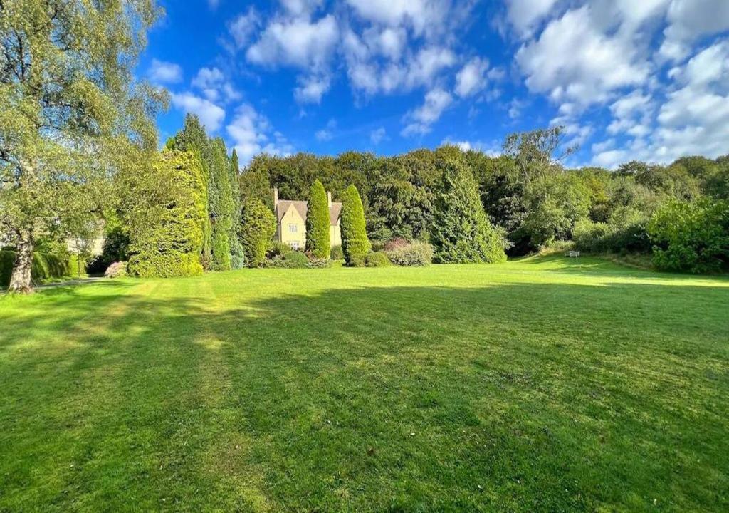 un gran campo verde con una casa y árboles en Perfect Cotswold Home with vast stunning Ground's, en Painswick