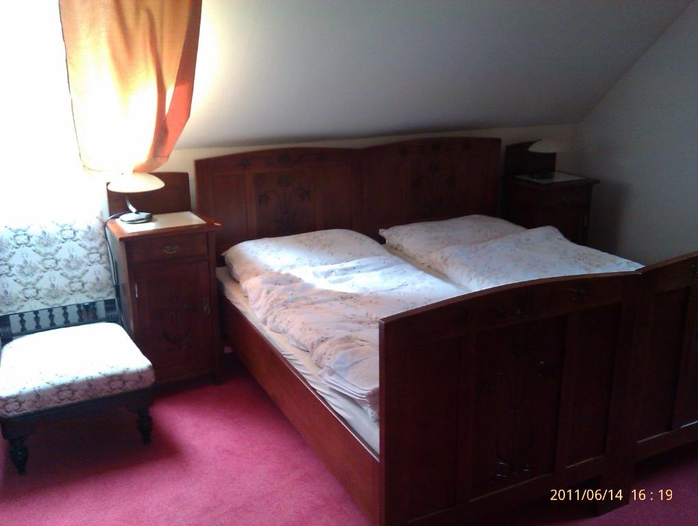 1 dormitorio con cama de madera, lámpara y silla en Penzion U Kata, en Bruntál