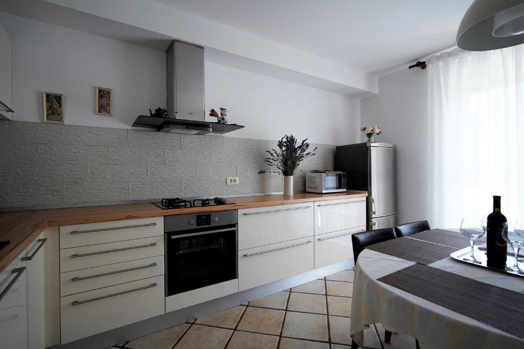 una cucina con armadi bianchi e un tavolo con una bottiglia di vino di Apartman Nada I a Fažana