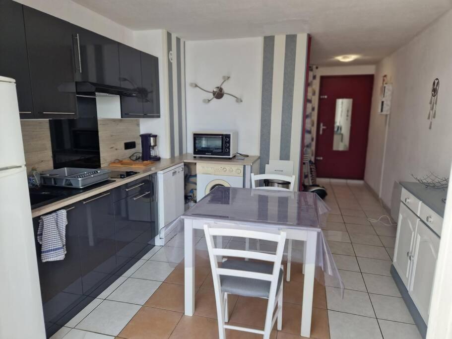 une cuisine avec une table et quelques chaises dans l'établissement Agréable appartement 3 Personnes Port La Nouvelle RDC et petit jardin, à Port-la-Nouvelle