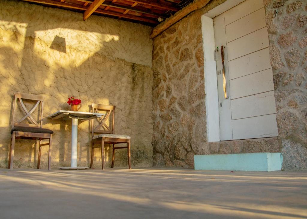 una mesa y dos sillas junto a una pared con una puerta en Paradise Camp en Monte das Gameleiras