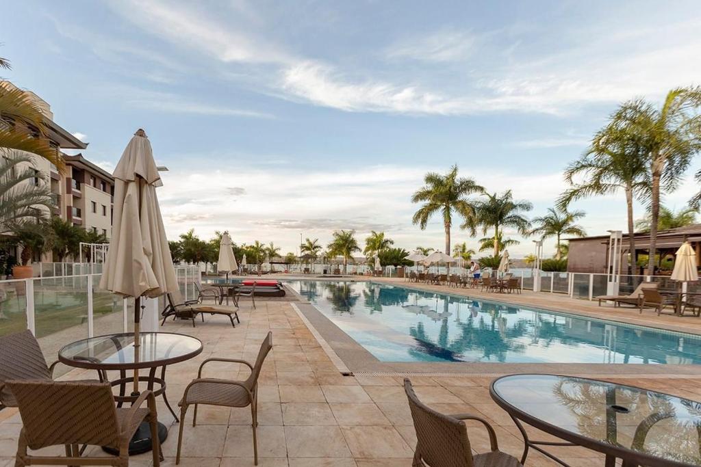 Una piscina con mesas y sillas al lado de un edificio. en Depto frente Lago Paranoá - CLR314, en Brasilia