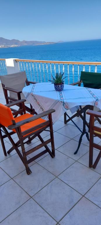 een tafel en stoelen op een balkon met uitzicht op de oceaan bij Mirabello Sea House in Agios Nikolaos